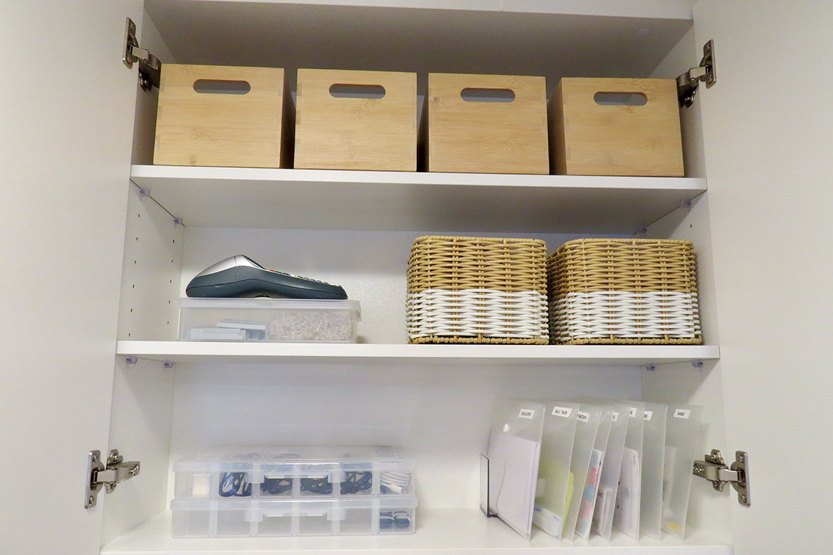 Cupboard organised with baskets, files and storage boxes